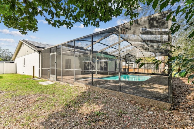 view of pool featuring a lawn and glass enclosure