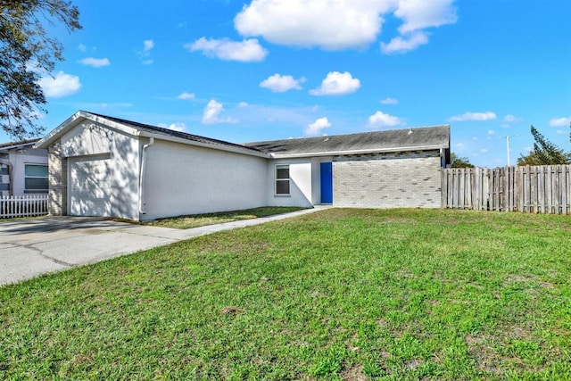 view of front of house with concrete driveway, an attached garage, fence, a front yard, and stucco siding