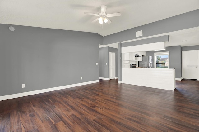 unfurnished living room with dark wood-style floors, vaulted ceiling, baseboards, and ceiling fan