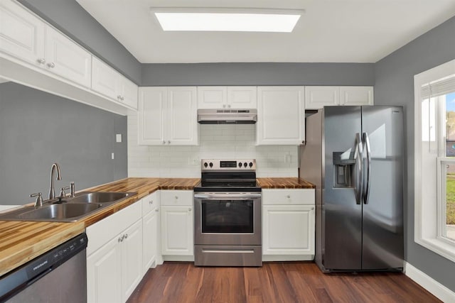 kitchen featuring dark wood finished floors, butcher block countertops, stainless steel appliances, under cabinet range hood, and a sink