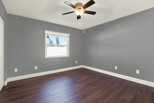 unfurnished room featuring dark wood finished floors, baseboards, and ceiling fan