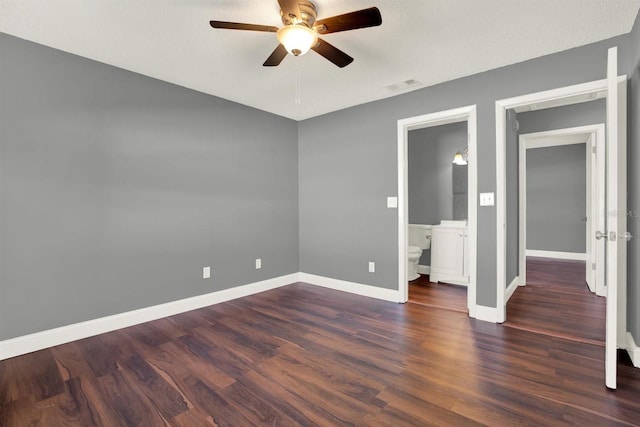 spare room featuring dark wood-style floors, visible vents, ceiling fan, and baseboards