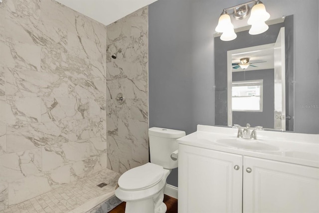 full bath with toilet, a tile shower, vanity, and a ceiling fan