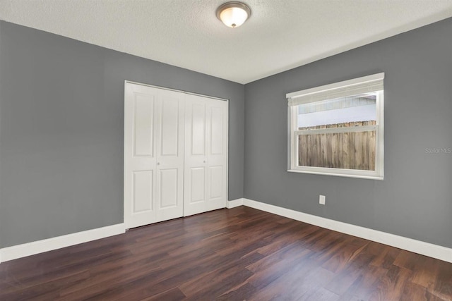 unfurnished bedroom with baseboards, dark wood finished floors, and a closet