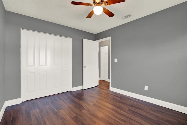 unfurnished bedroom with a closet, visible vents, ceiling fan, wood finished floors, and baseboards