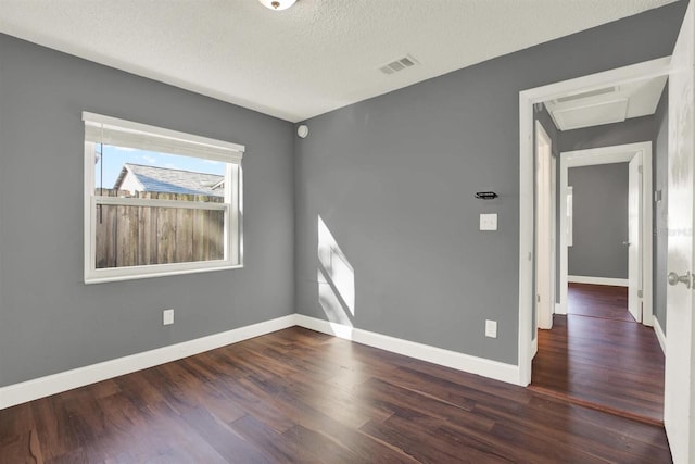 unfurnished room featuring baseboards, a textured ceiling, visible vents, and wood finished floors