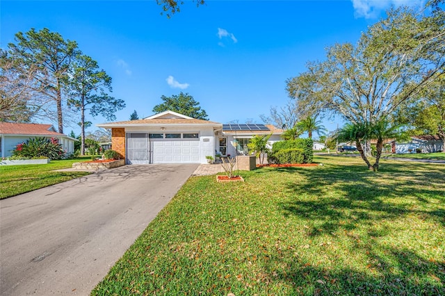 ranch-style house featuring a front lawn, solar panels, and a garage