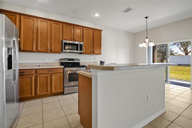 kitchen featuring light countertops, light tile patterned floors, brown cabinets, appliances with stainless steel finishes, and a notable chandelier