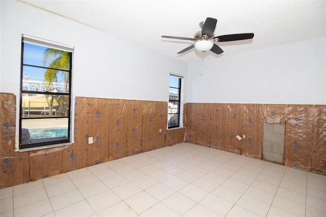 unfurnished room featuring wooden walls and ceiling fan