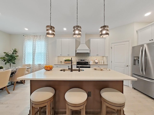 kitchen featuring pendant lighting, sink, white cabinets, a kitchen island with sink, and stainless steel appliances