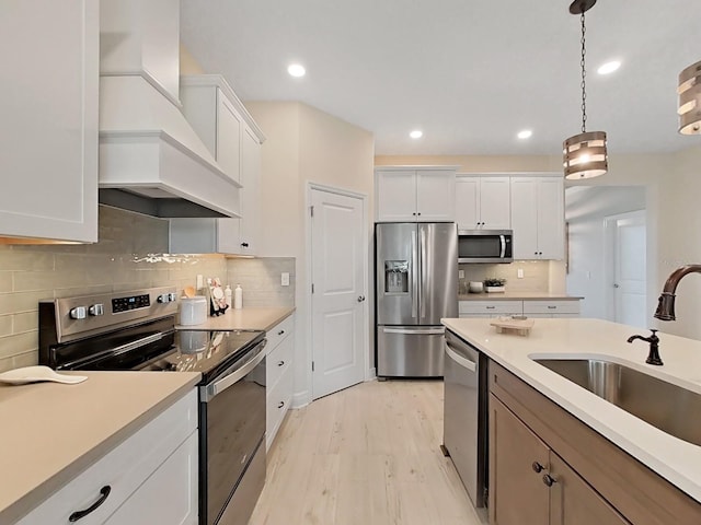 kitchen with hanging light fixtures, custom range hood, white cabinets, and appliances with stainless steel finishes