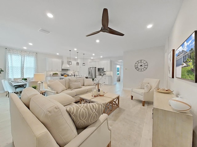 living room with sink, ceiling fan, and light wood-type flooring