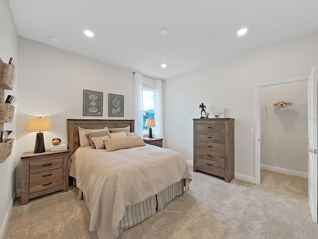 bedroom with a spacious closet and light colored carpet