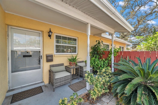 entrance to property featuring fence and stucco siding