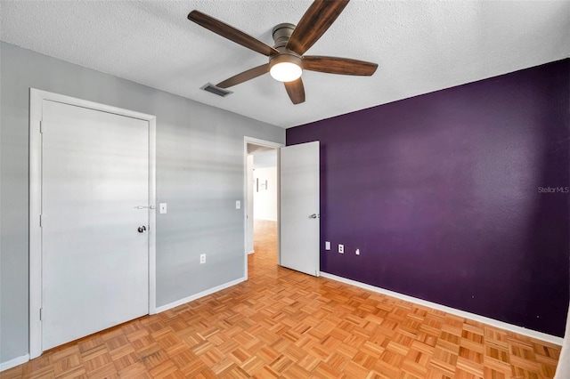 unfurnished bedroom featuring a ceiling fan, baseboards, visible vents, and a textured ceiling