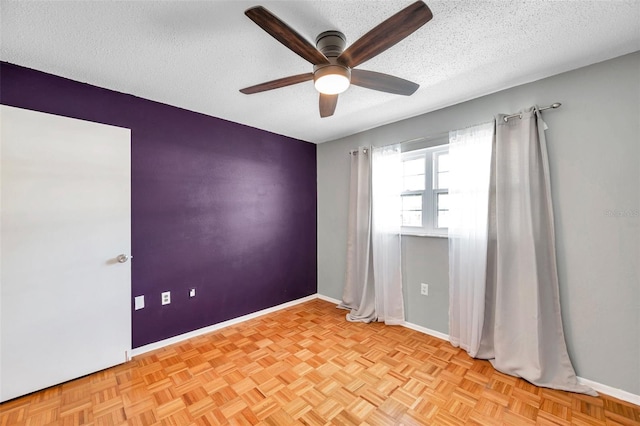 spare room featuring ceiling fan, baseboards, and a textured ceiling