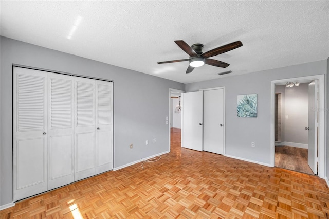 unfurnished bedroom with a textured ceiling, a ceiling fan, visible vents, and baseboards