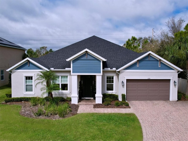 ranch-style home featuring an attached garage, a shingled roof, decorative driveway, and a front yard