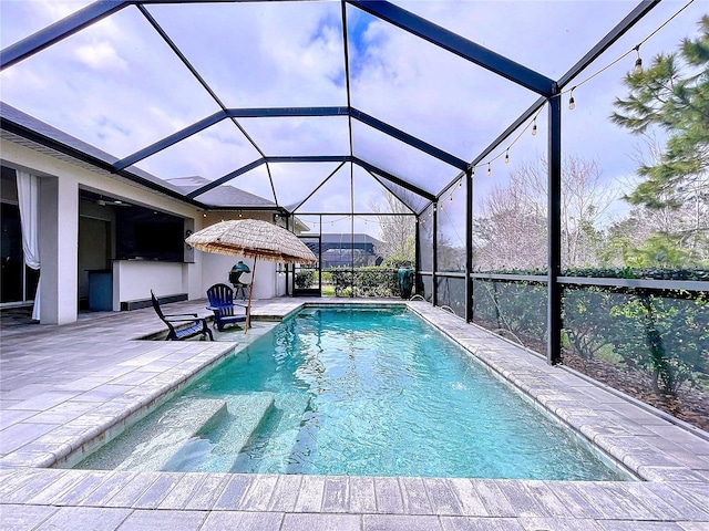 outdoor pool featuring glass enclosure and a patio area