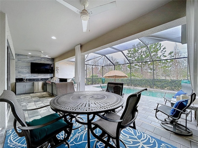 view of patio featuring an outdoor kitchen, a lanai, a sink, a ceiling fan, and an outdoor pool