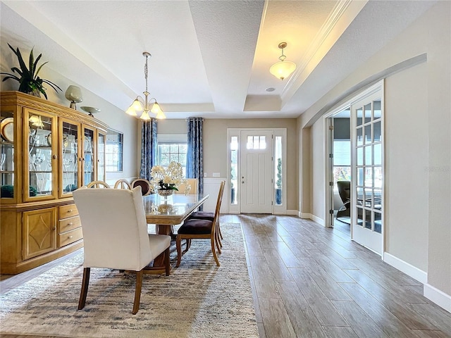 dining area with baseboards, wood finished floors, an inviting chandelier, a tray ceiling, and a textured ceiling