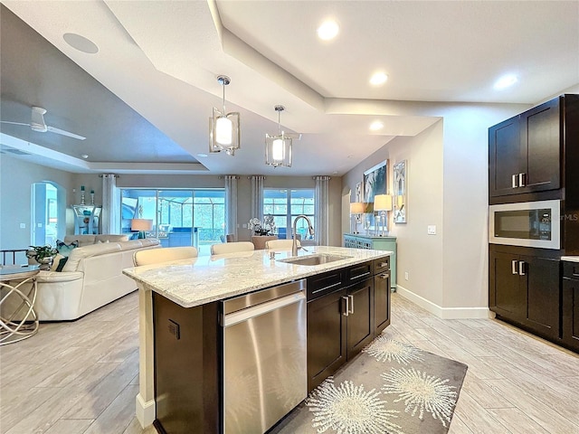 kitchen with stainless steel appliances, a tray ceiling, a sink, and arched walkways