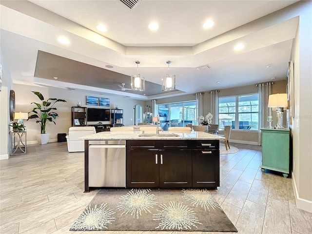 kitchen with a raised ceiling, open floor plan, a sink, pendant lighting, and stainless steel dishwasher