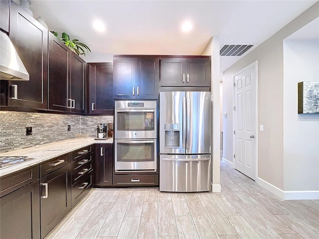 kitchen featuring stainless steel appliances, visible vents, decorative backsplash, wood tiled floor, and wall chimney exhaust hood