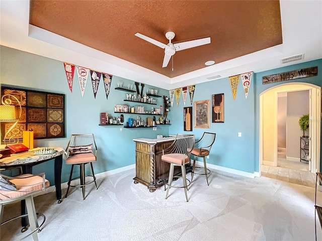 bar featuring visible vents, arched walkways, baseboards, a tray ceiling, and a bar