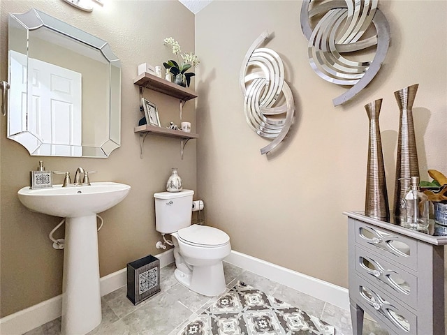 half bath with tile patterned floors, toilet, and baseboards