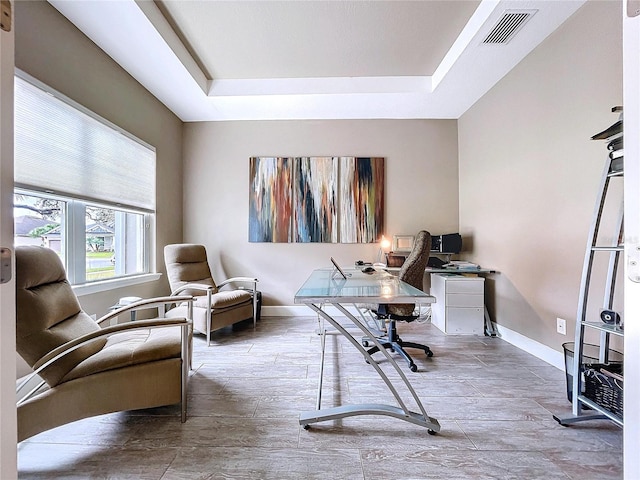 home office featuring a tray ceiling, visible vents, baseboards, and wood finished floors