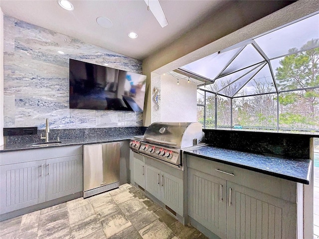 view of patio / terrace featuring glass enclosure, a sink, an outdoor kitchen, and area for grilling