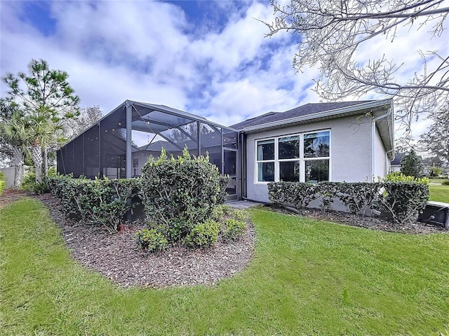 exterior space featuring a yard, glass enclosure, and stucco siding