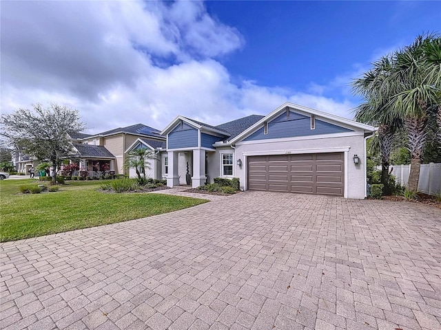 view of front of house with decorative driveway, an attached garage, fence, and a front yard