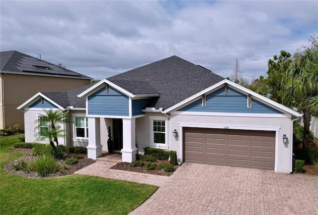 view of front of house with roof with shingles, an attached garage, decorative driveway, a front lawn, and stucco siding