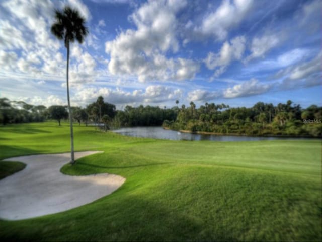 view of home's community with view of golf course, a water view, and a lawn