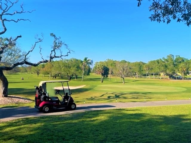 view of property's community with golf course view and a lawn