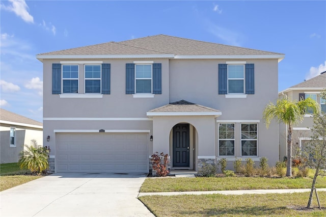 traditional home with driveway, roof with shingles, an attached garage, and stucco siding