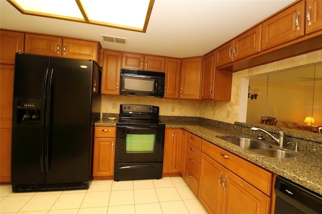 kitchen with light tile patterned flooring, sink, dark stone countertops, decorative backsplash, and black appliances