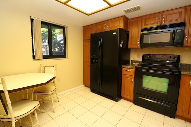 kitchen with light tile patterned floors, black appliances, and dark stone counters