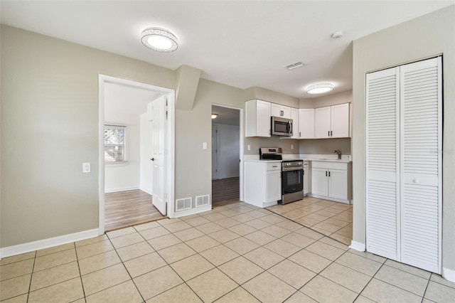 kitchen featuring light tile patterned floors, sink, white cabinets, and appliances with stainless steel finishes