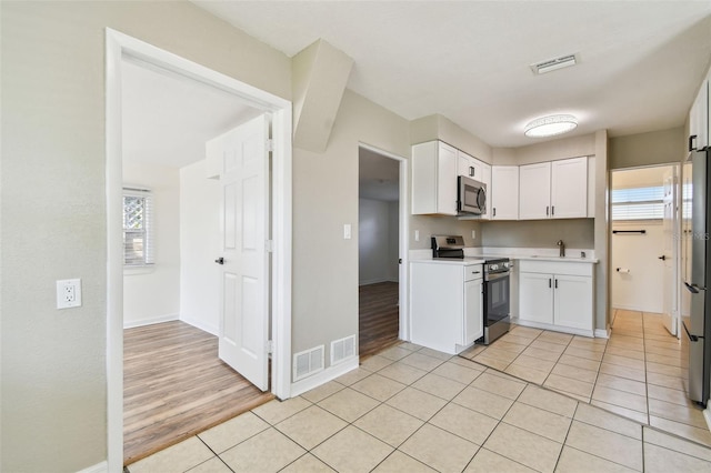 kitchen featuring white cabinetry, light tile patterned floors, and appliances with stainless steel finishes