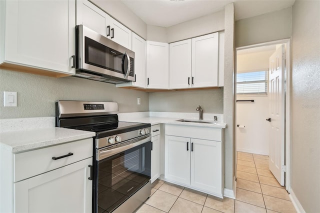 kitchen featuring sink, light tile patterned flooring, white cabinets, and appliances with stainless steel finishes