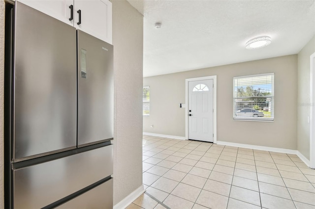 foyer entrance featuring light tile patterned flooring, plenty of natural light, and a textured ceiling