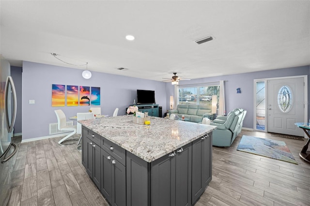 9911 Antilles Dr, Seminole, FL 33776 - kitchen with light wood finished floors, visible vents, open floor plan, and freestanding refrigerator