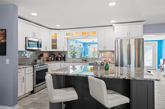 9911 Antilles Dr, Seminole, FL 33776 - kitchen featuring stainless steel appliances, glass insert cabinets, a kitchen breakfast bar, and a kitchen island