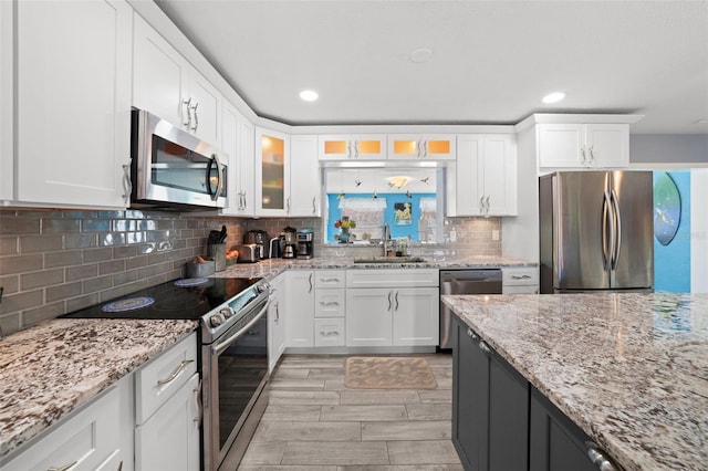 9911 Antilles Dr, Seminole, FL 33776 - kitchen featuring light stone counters, stainless steel appliances, glass insert cabinets, white cabinets, and a sink
