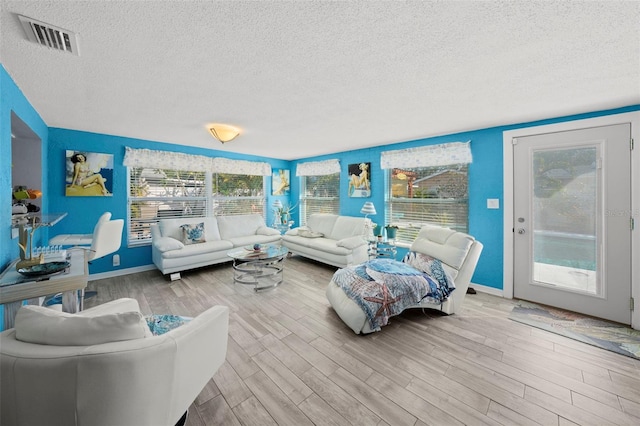 9911 Antilles Dr, Seminole, FL 33776 - living area featuring light wood finished floors, baseboards, visible vents, and a textured ceiling