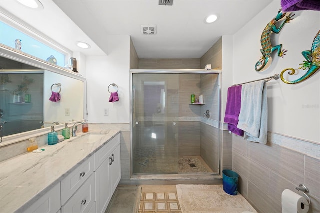 9911 Antilles Dr, Seminole, FL 33776 - bathroom featuring visible vents, a stall shower, vanity, and tile walls