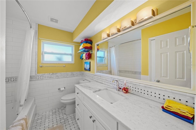 9911 Antilles Dr, Seminole, FL 33776 - full bathroom with tile walls, visible vents, toilet, shower / bath combo, and vanity